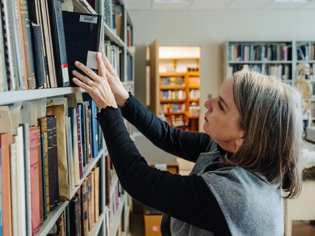 Jennifer Langford reaching for a book on a bookshelf.