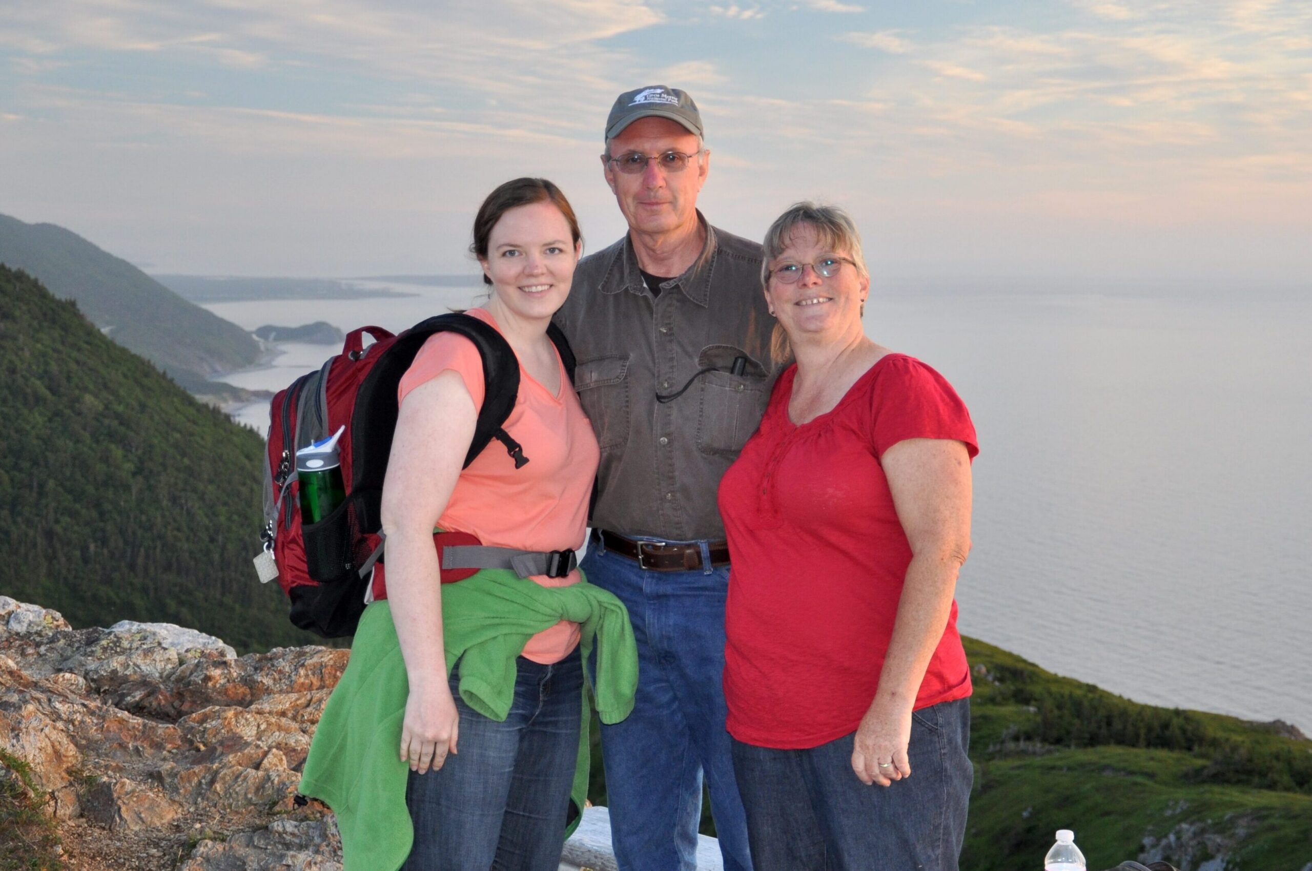 Dr. Stacey Lane Evans and her parents pose at the top of a cliff overseeing a body of water.